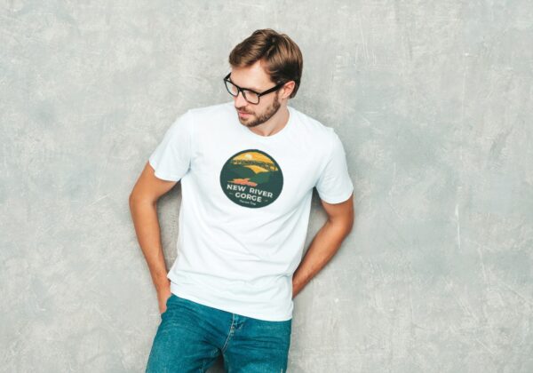 man with glasses wearing a white tshirt with new river gorge national park design on it with new river gorge bridge mountains and sunset