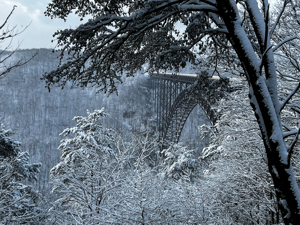 Winter view of New River Gorge Bridge in West Virginia, surrounded by snowy landscape.
