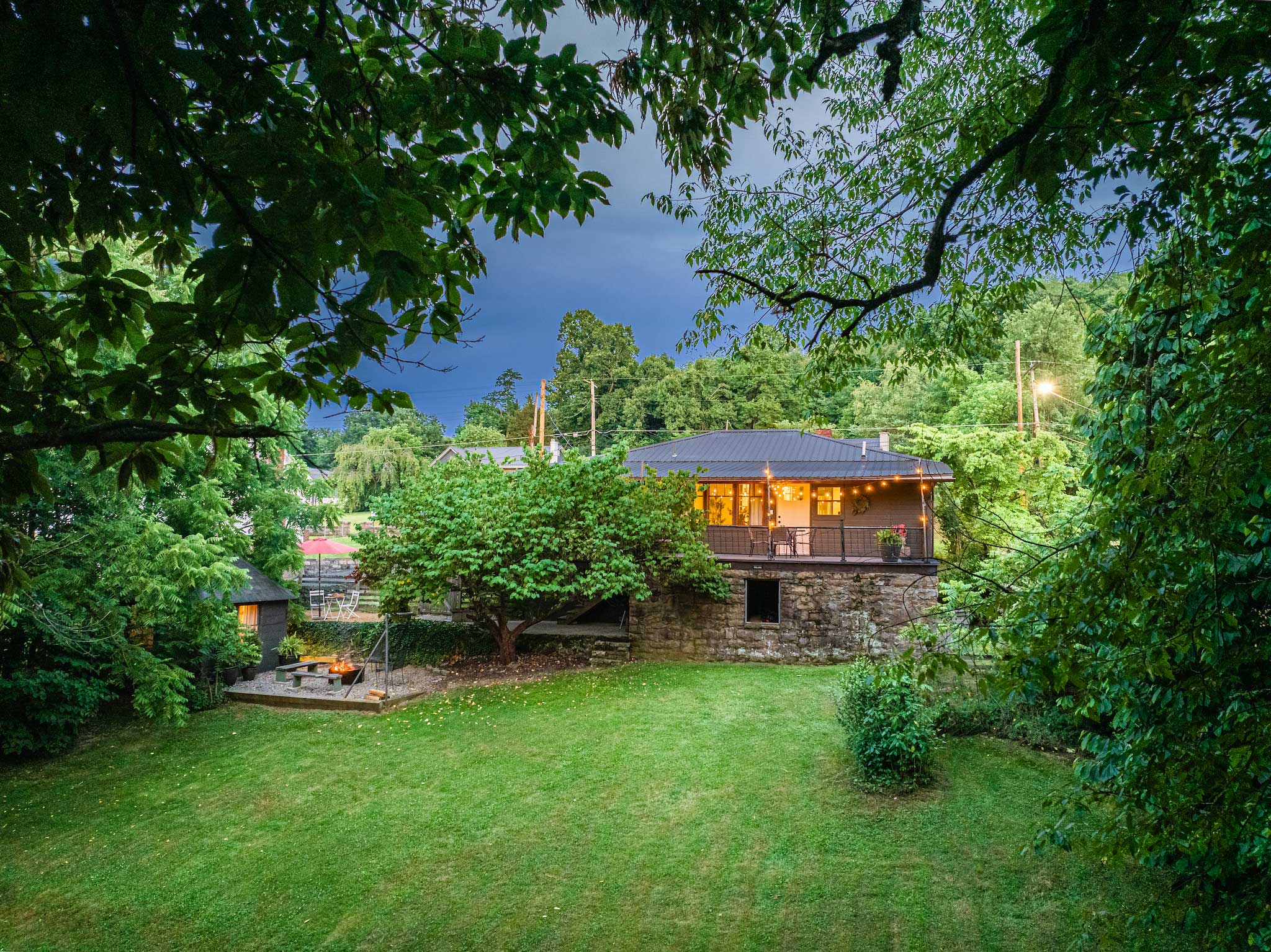 DT Bungalow property at dusk — wide green lawn, string lights glowing